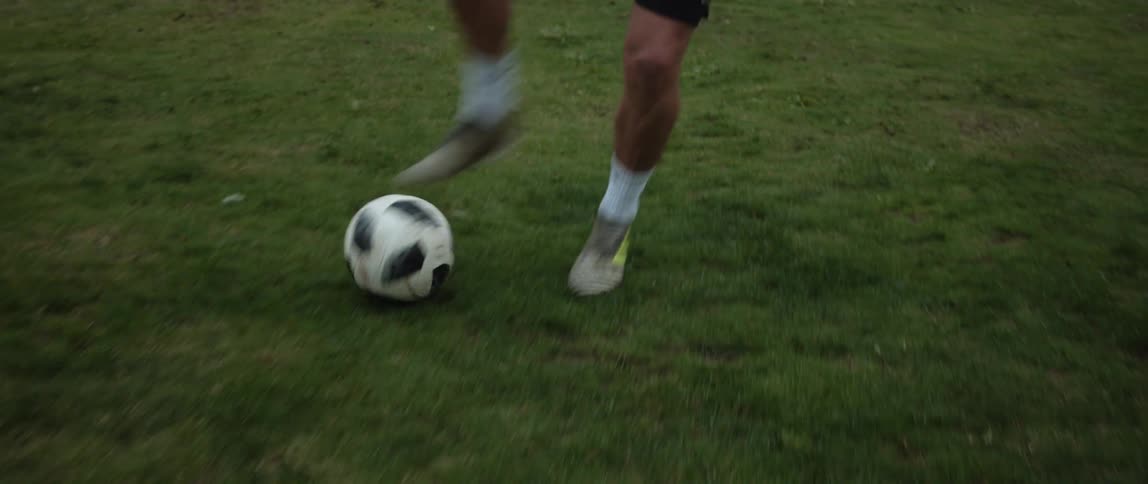 A man kicks a soccer ball down a field