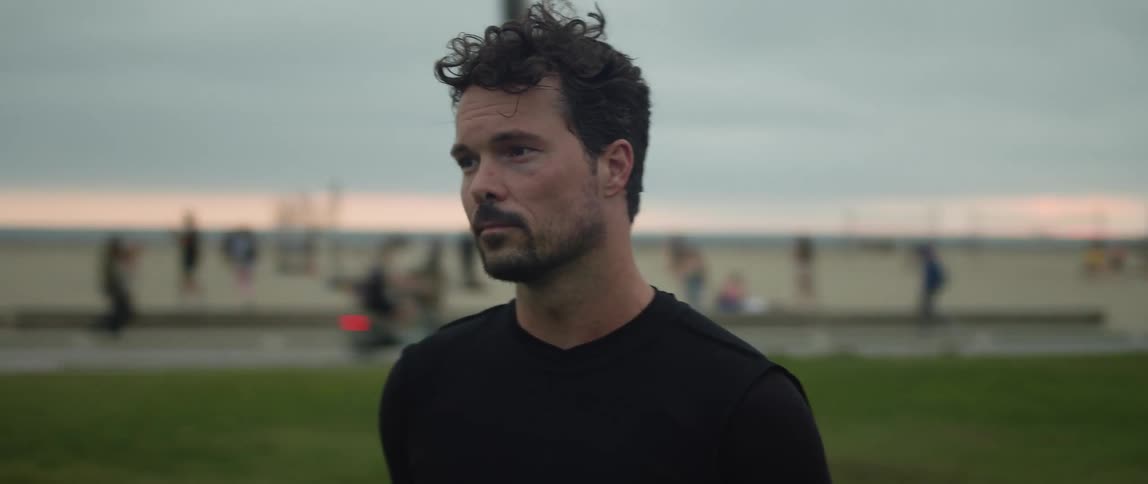 A man looks around as he stands on a lawn near the beach