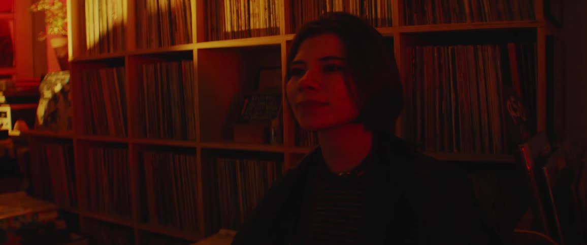 A person sitting in a dark room smiling and relaxing