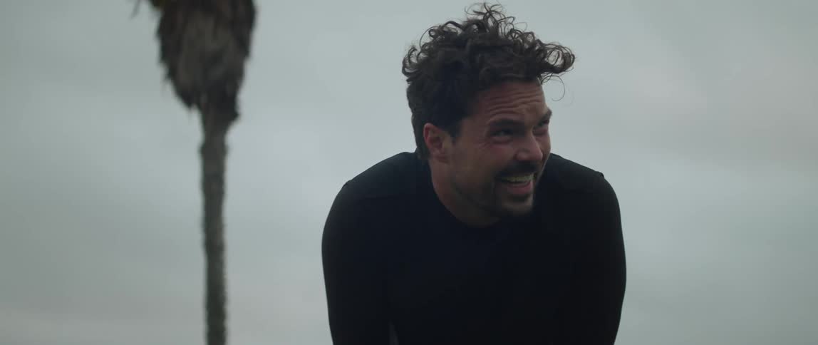 A man is bent over looking forward with a nervous and determined look on his face seemingly tense and blowing out breaths