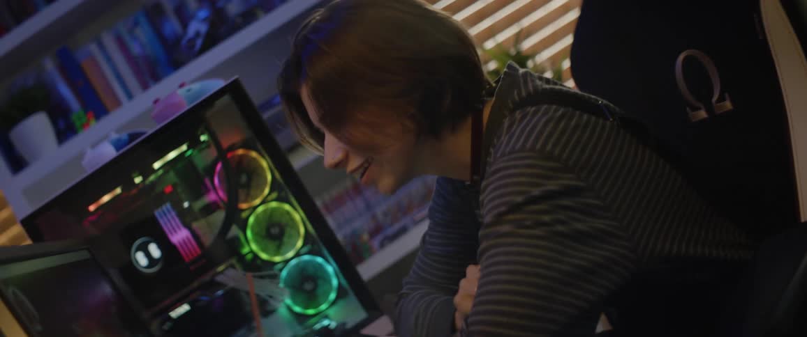 A teenage girl sits at home and video chats on her computer