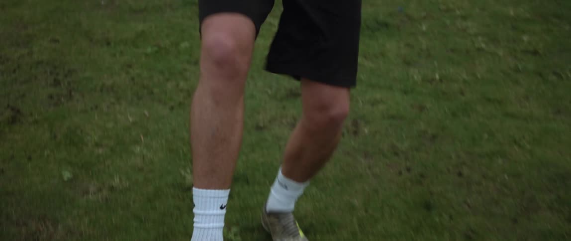 A man kicking around soccer ball on a grassy field