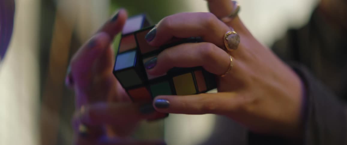 A woman with a lot of rings is solving a rubiks cube