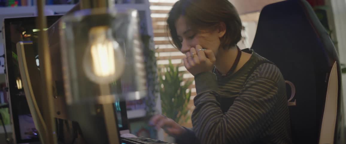 Woman sitting at desk with large monitor types on keyboard and smiles