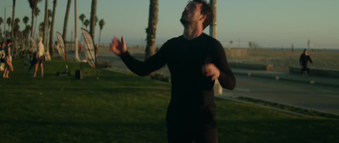 A man kicks up a soccer ball practicing his footwork on the grass near the beach