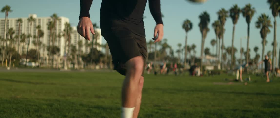 Man plays with a soccer ball in busy park