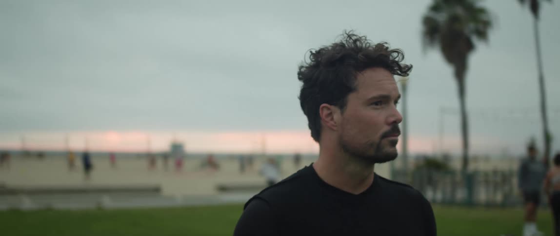 A man with a soccer ball is standing in a field at the beach