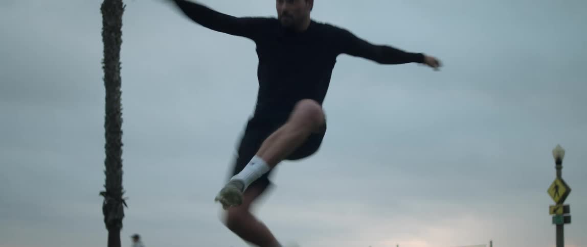 Man jumps while practicing with soccer ball in park