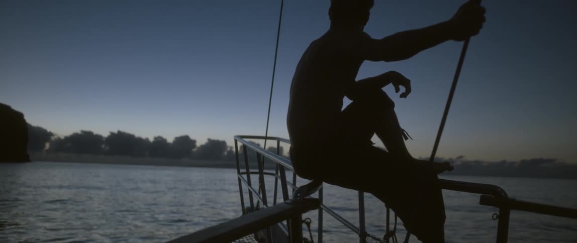 Man sitting on the railing of a ship