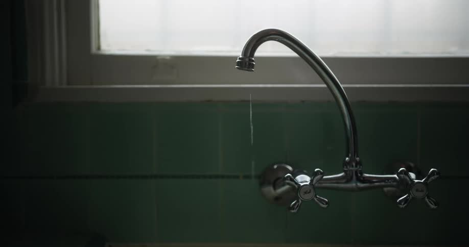 A person turning off a leaky faucet