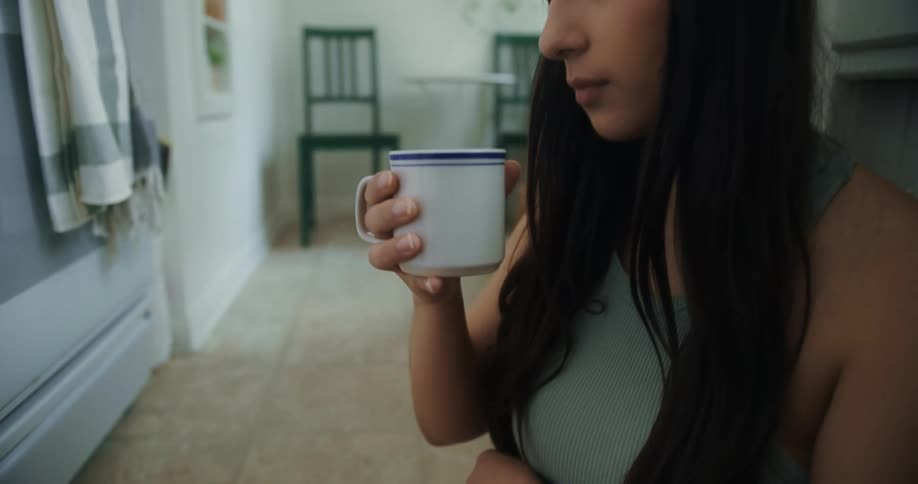 A woman is sitting down and drinking a beverage