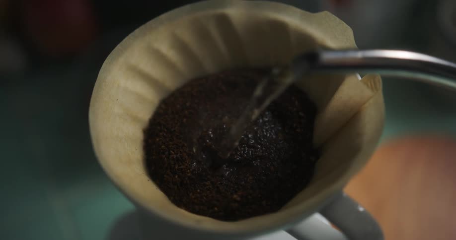 Water being poured over coffee grounds as someone makes coffee at home