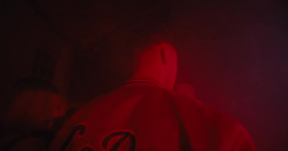 Man with mustache and jacket looks over his shoulders and walks away in the club