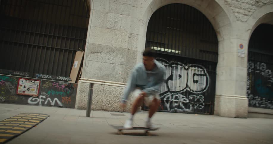 A man rides his skateboard over a speedbump in front of a city building