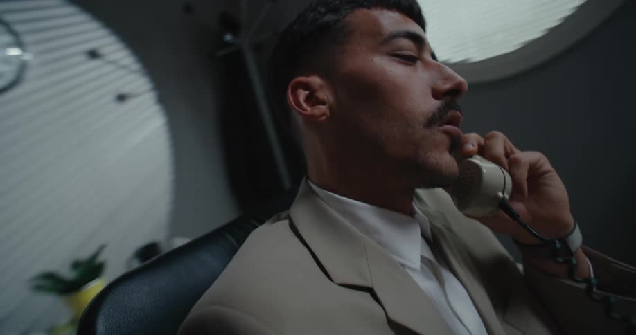 Man with moustache beige suit talks on phone at the office