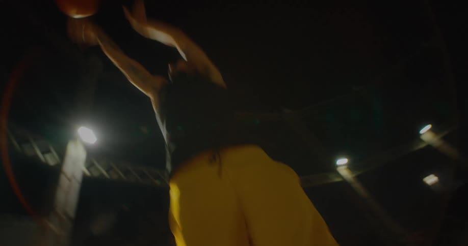 A man playing basketball outdoors at night