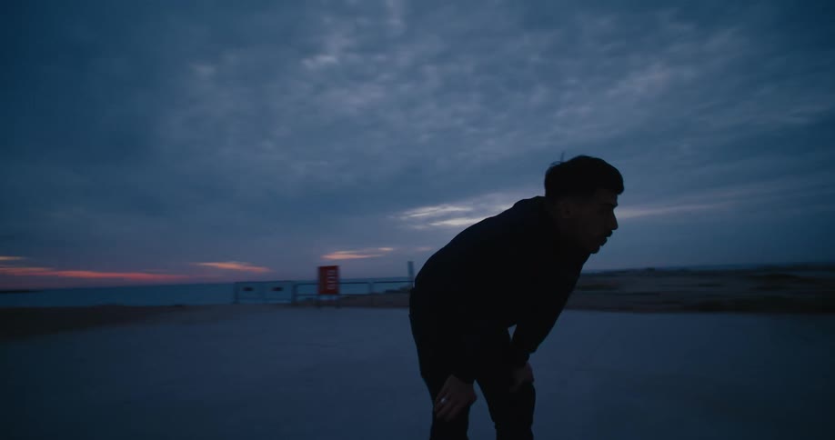 Man resting his hands on his knees to recover from a hard effort at dusk