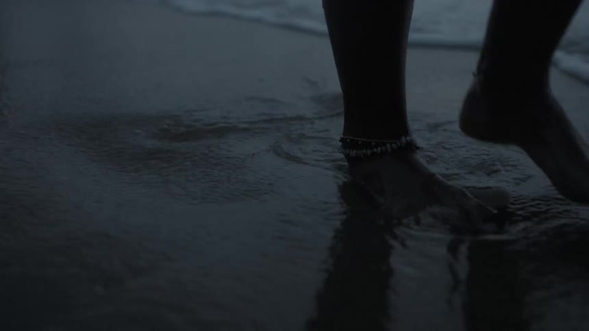 Persons slowly moving and crossing their feet as the gentle waves flow over them
