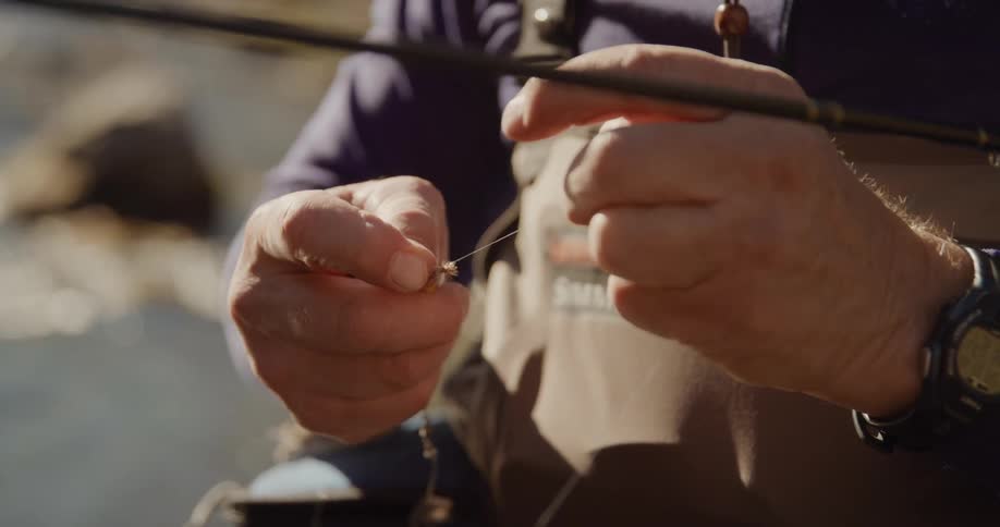 A man baits a hook while fishing