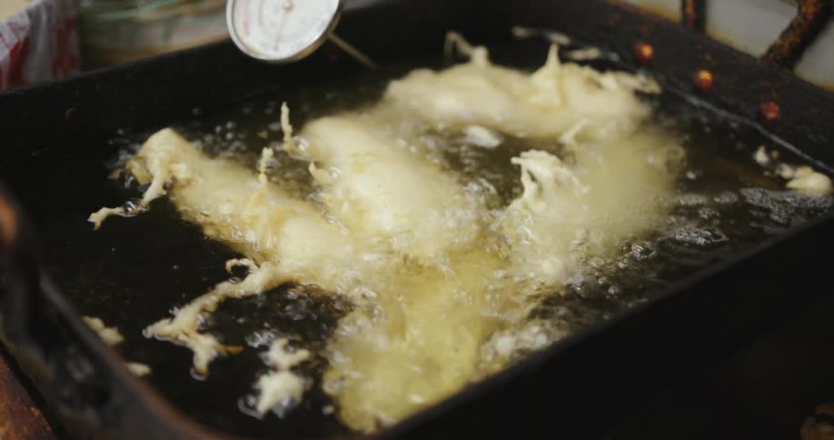 Food covered in batter being cooked in a deep fryer