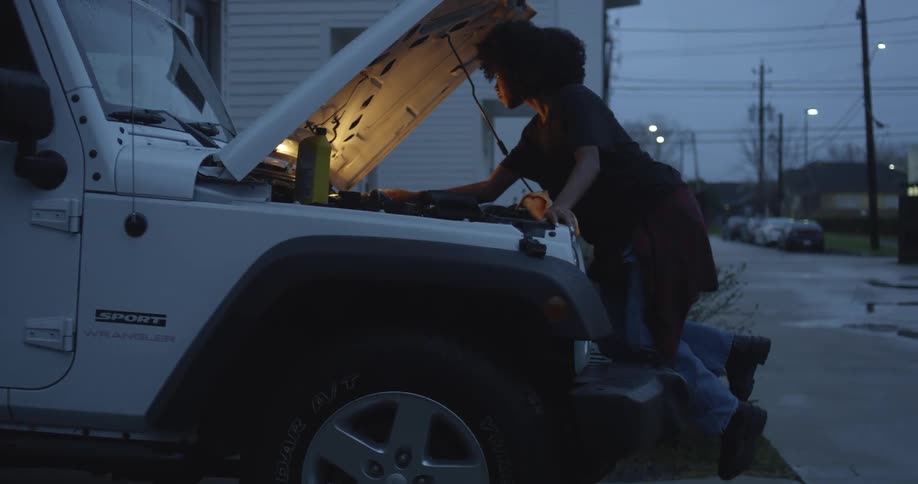 Young woman cleaning the engine of a vehicle on the front porch at morning