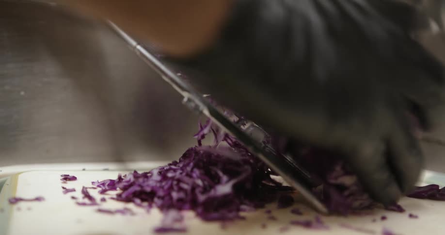 Someone is standing over a table and grating a purple onion