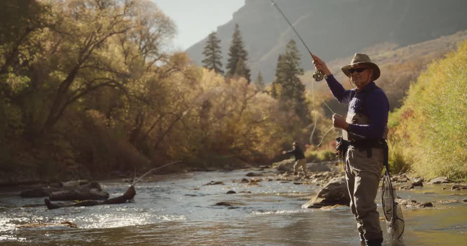 Two men stand in a river and cast their fishing lines