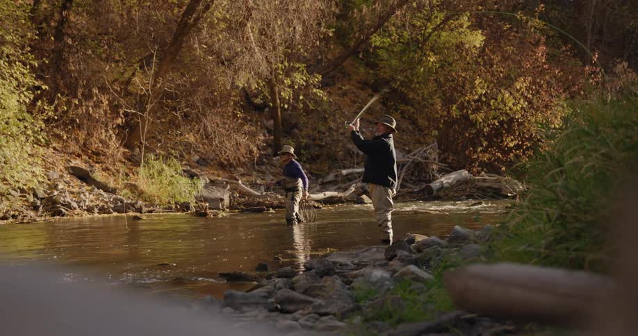 Two men standing on a shallow river fly fishing in the morning