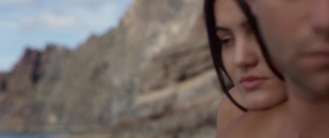 Close-up of a woman resting her head on a man's shoulder at the beach