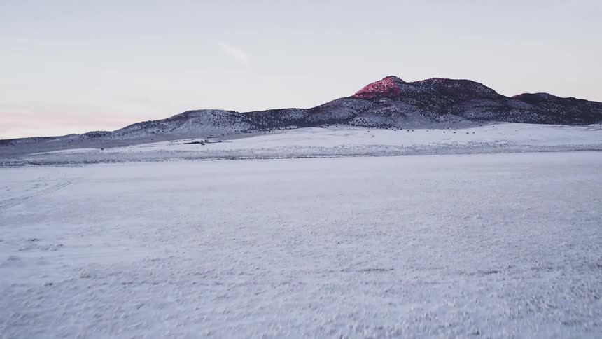 Snow covers the open clearing beside a mountain