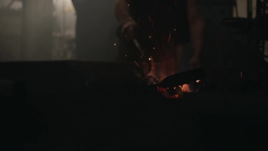 Blacksmith makes fire in the fireplace poking fire