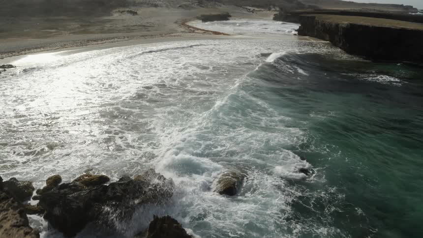 Traversing over a sea cliff to reveal waves breaking along the shoreline below