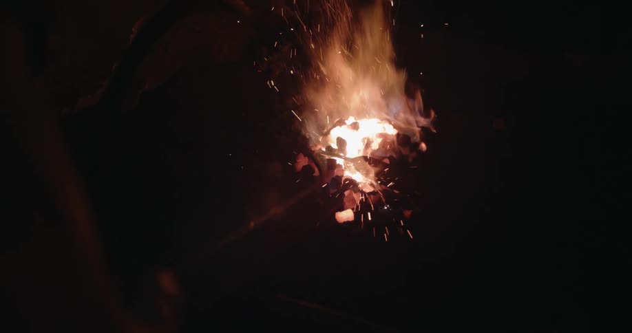 A person with tool uses it to push and contain a small intensely burning fire
