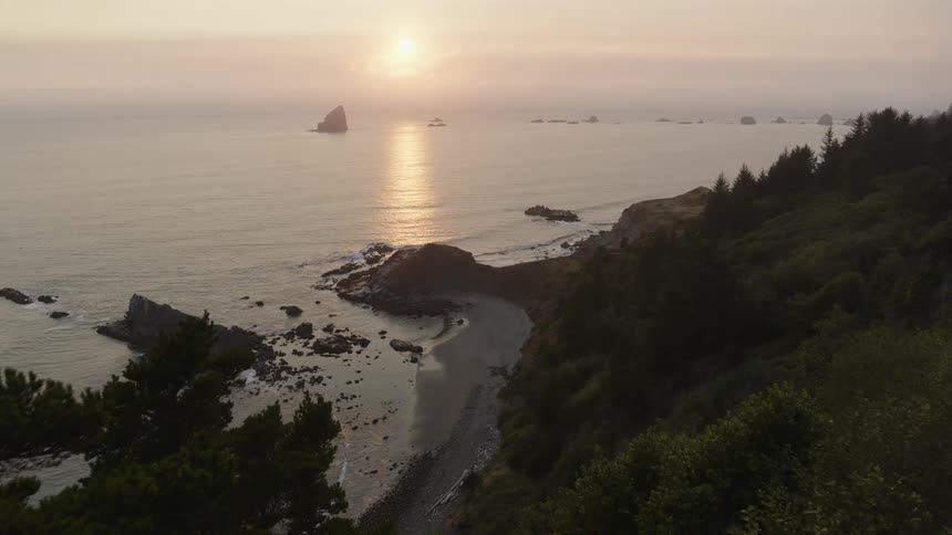Reveal of calm waves lapping the shoreline of a secluded beach along a lush cliffside