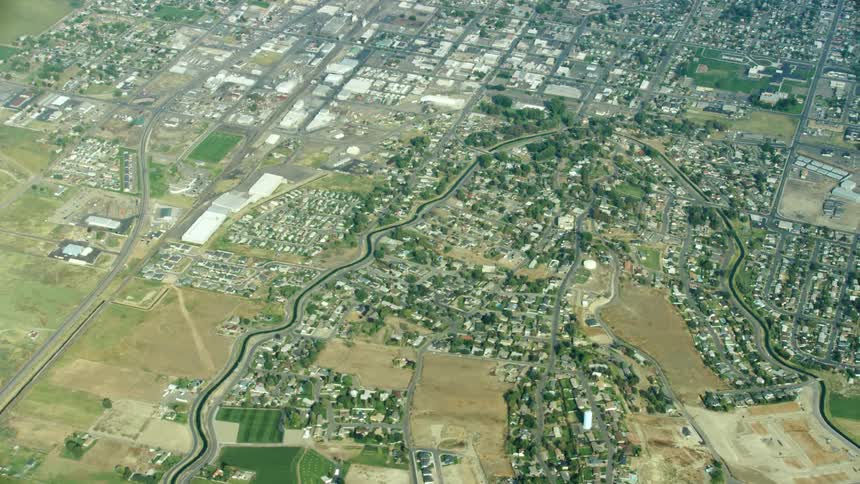 High altitude aerial shot of a u-shaped irrigation canal as it weaves through suburban neighborhood in the arid and dry desert west
