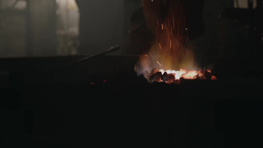 Blacksmith pokes fire with fire iron
