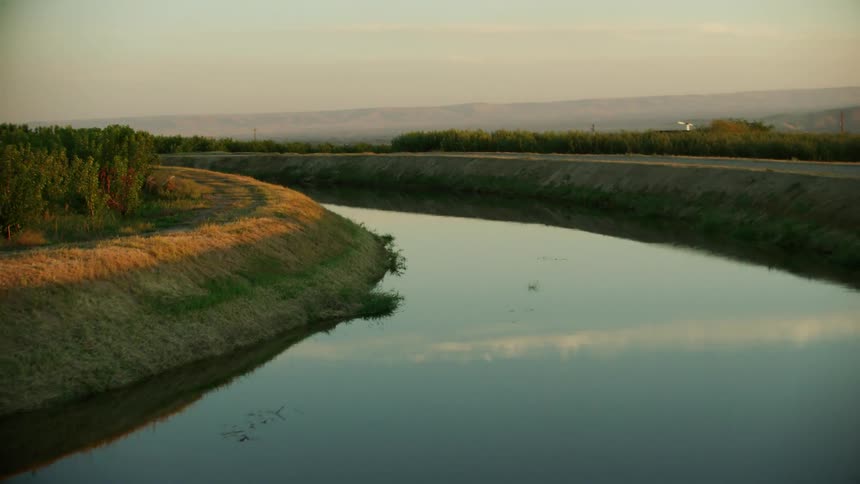 Dynamic shot of a sunset reflection in an irrigation canal as it runs through the western united states