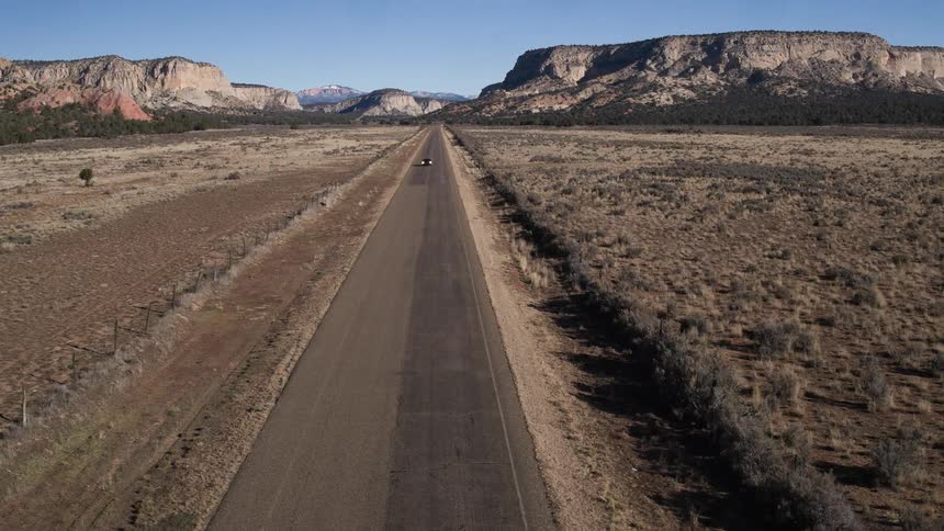 A vehicle traveling down a deserted road in the day