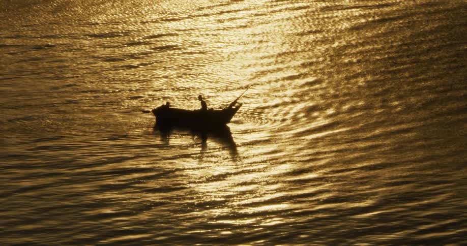 A person travels along a lake in a boat at sunset