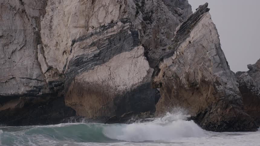 The waves crash against the rocks