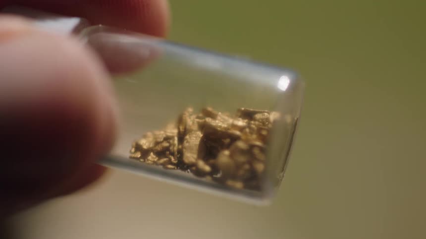A person turns a small tube containing minerals in their hand