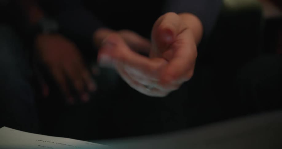 Two people are sitting and one waves their hand around