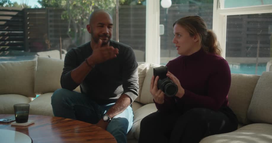 Man and woman are talking on a couch and holding a camera