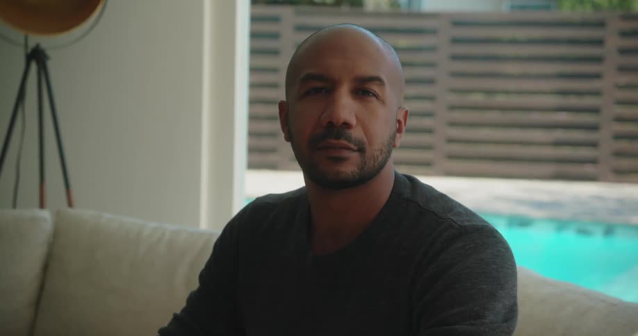A man sits and holds his hands in various positions as he poses for the camera