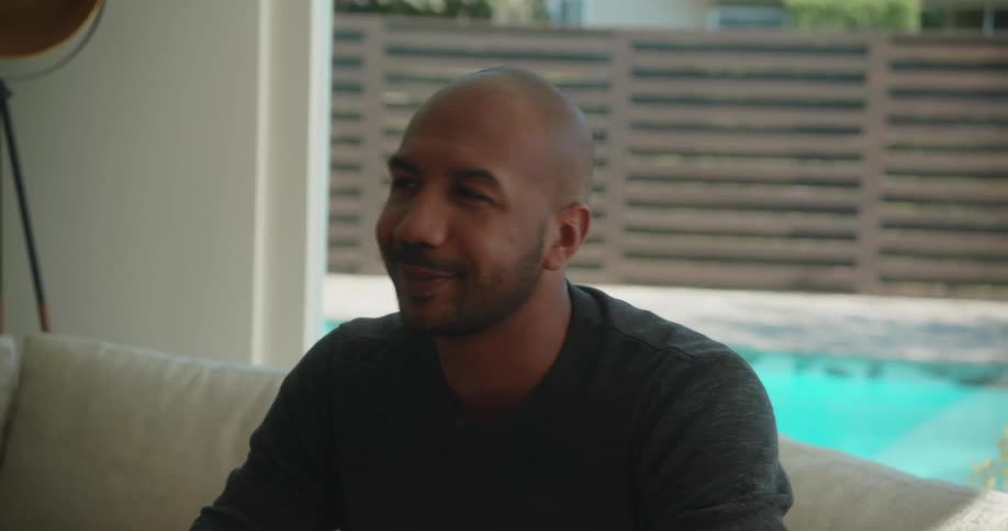 A man laughs while talking on the couch
