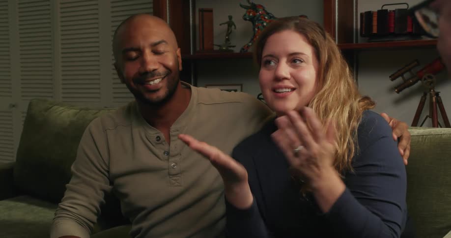 A couple hug while talking with someone at home