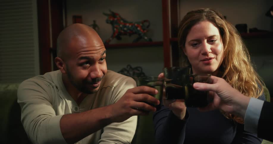A man and woman raise their glasses with another individual before taking a drink