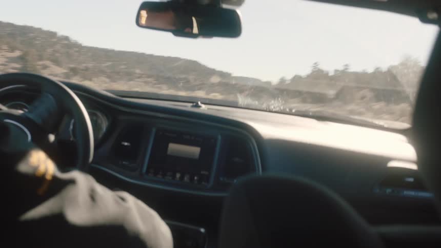 A man is driving a car fast on a dirt area