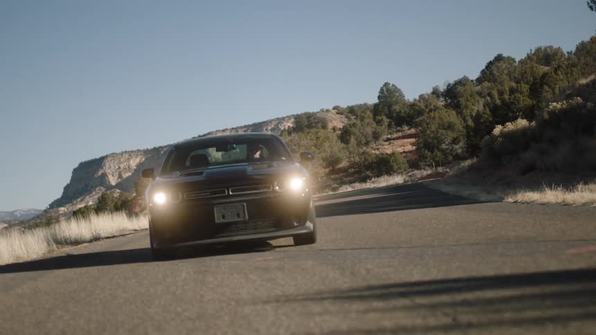 A car drives down a road with its headlights on