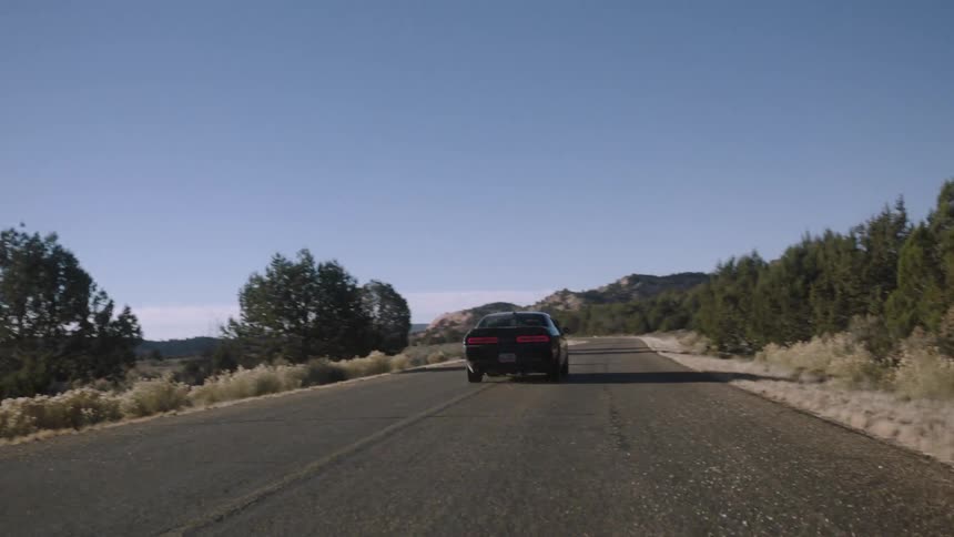 A black car races down a road